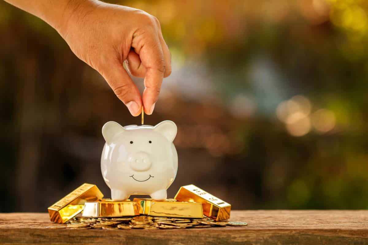 Barres d'or et pièces disposées sur un bureau avec un graphique des prix en arrière-plan